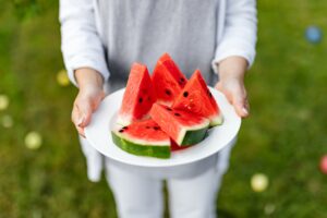 person holding sliced watermelonwith seeds on white ceramic plate
